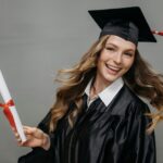 Happy woman in graduation gown with diploma, celebrating her achievement.