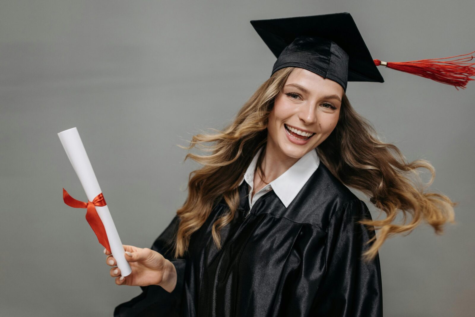 Happy woman in graduation gown with diploma, celebrating her achievement.